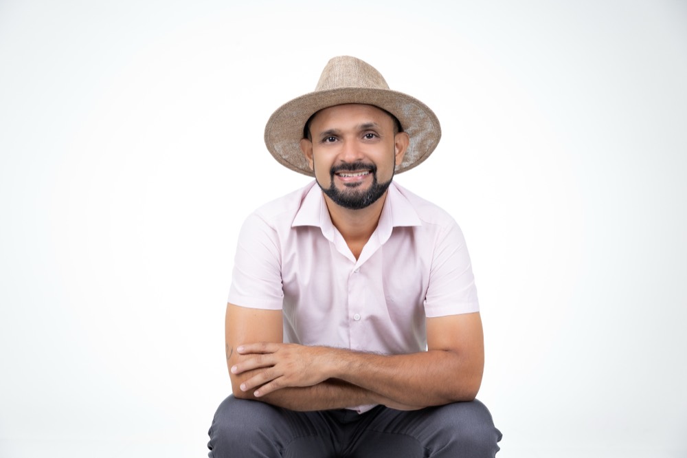 Dr. Casimiro Junior sentado, braços cruzados, camisa rosa